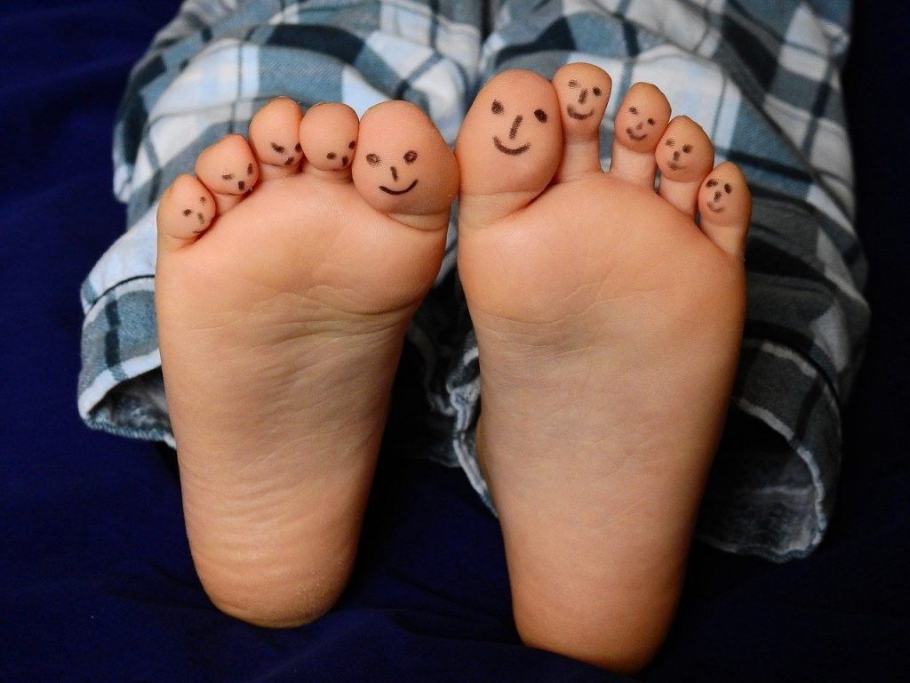 pieds nus d'un enfant avec des petits personnages souriants sur les orteils
