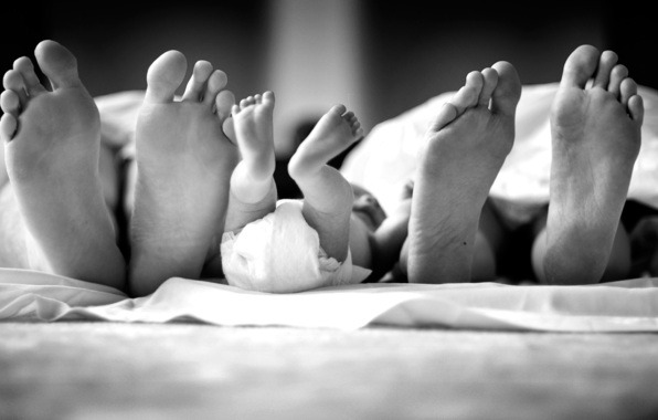 pieds de parents et d'un bébé sous la couette